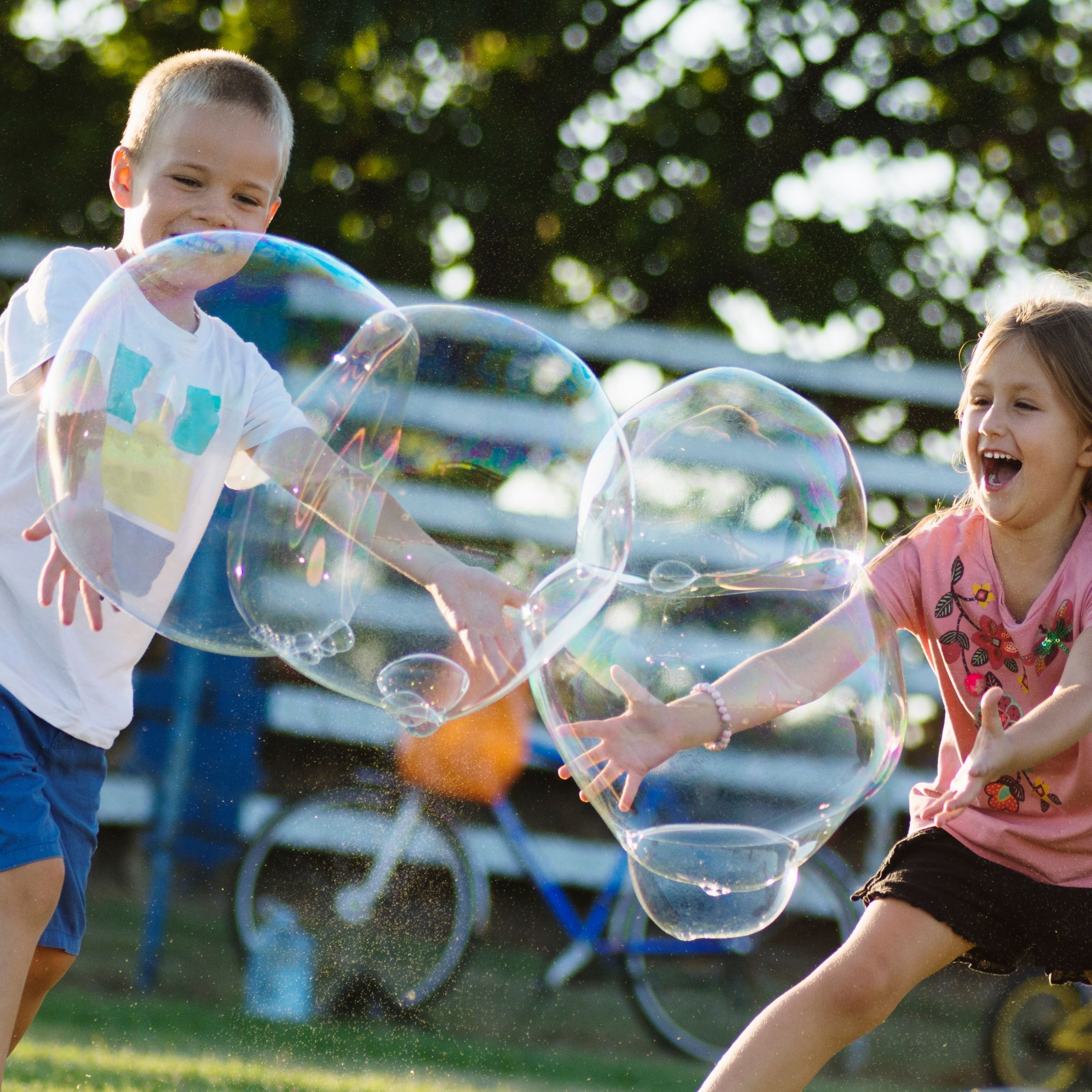 zwei spielende Kinder mit riesenseifenblasen
